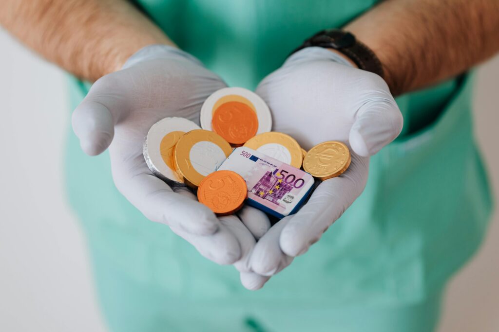 zipwp-image-4021809 A healthcare worker with gloves holding Euro coins and a bill, symbolizing medical finance.